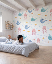 Papier peint enfant Moby, garçon allongé devant le mur aux baleines pastel, Wonderwall Casablanca