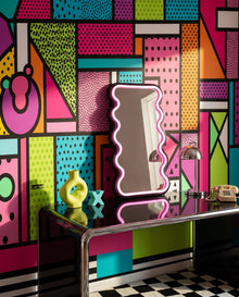 Fresque murale Milano en gros plan derrière un bureau en laque noire et un miroir ondulé : papier peint Memphis sur mesure Wonderwall