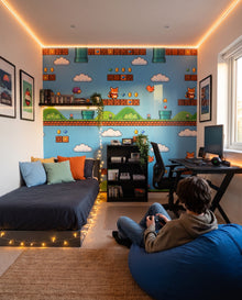 Fresque murale Warp dans une chambre d'adolescent, manette en main sur un pouf bleu : décor 8-bit sur mesure au Maroc, Wonderwall